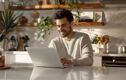 Man using laptop in bright kitchen