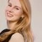 Blonde woman smiling softly in neutral setting