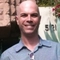 Bald man smiling outdoors by brick wall